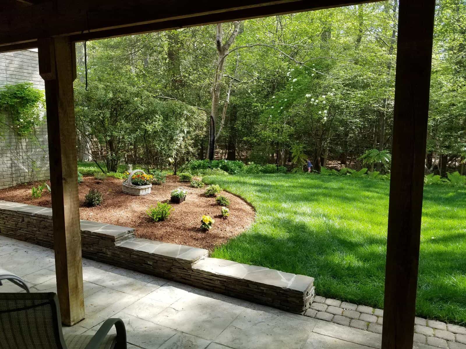 A patio with a view of a lush green lawn and trees.