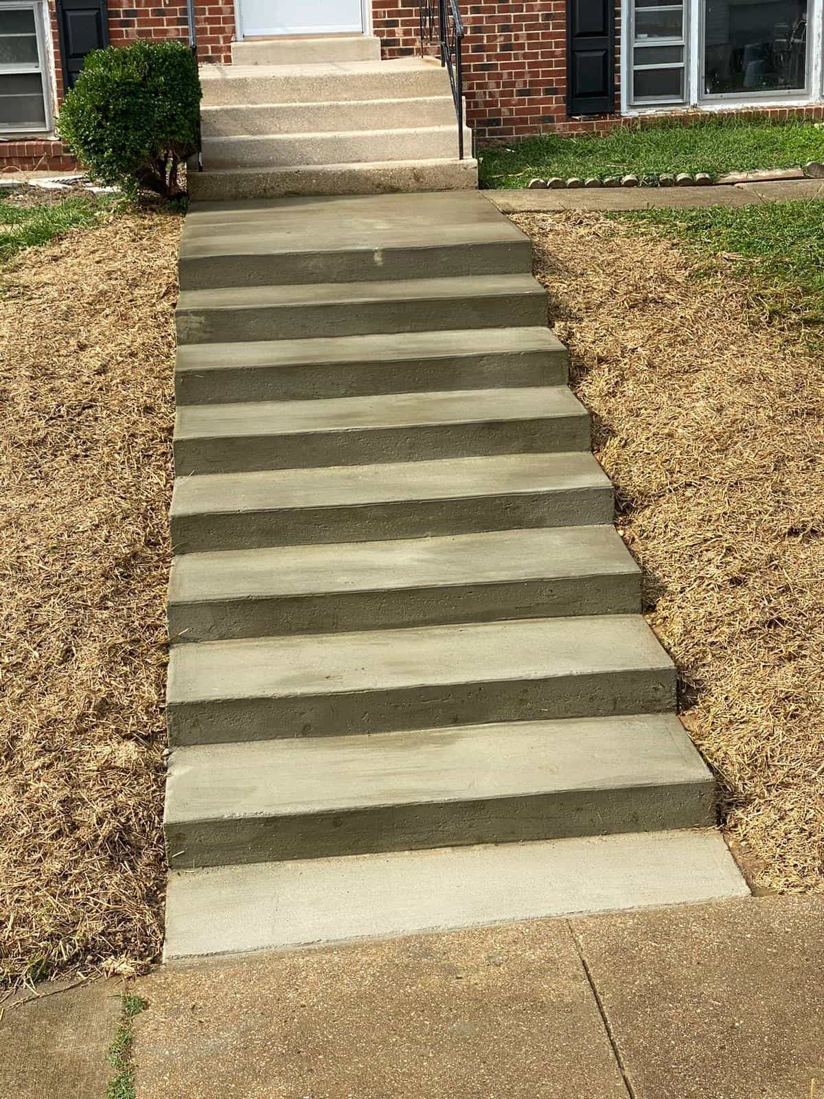 A set of concrete steps leading up to a brick house.
