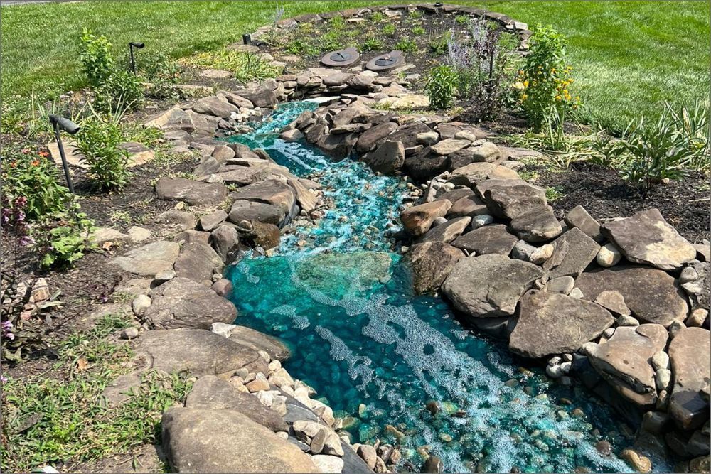 A stream of water is running through a rocky area in a garden.