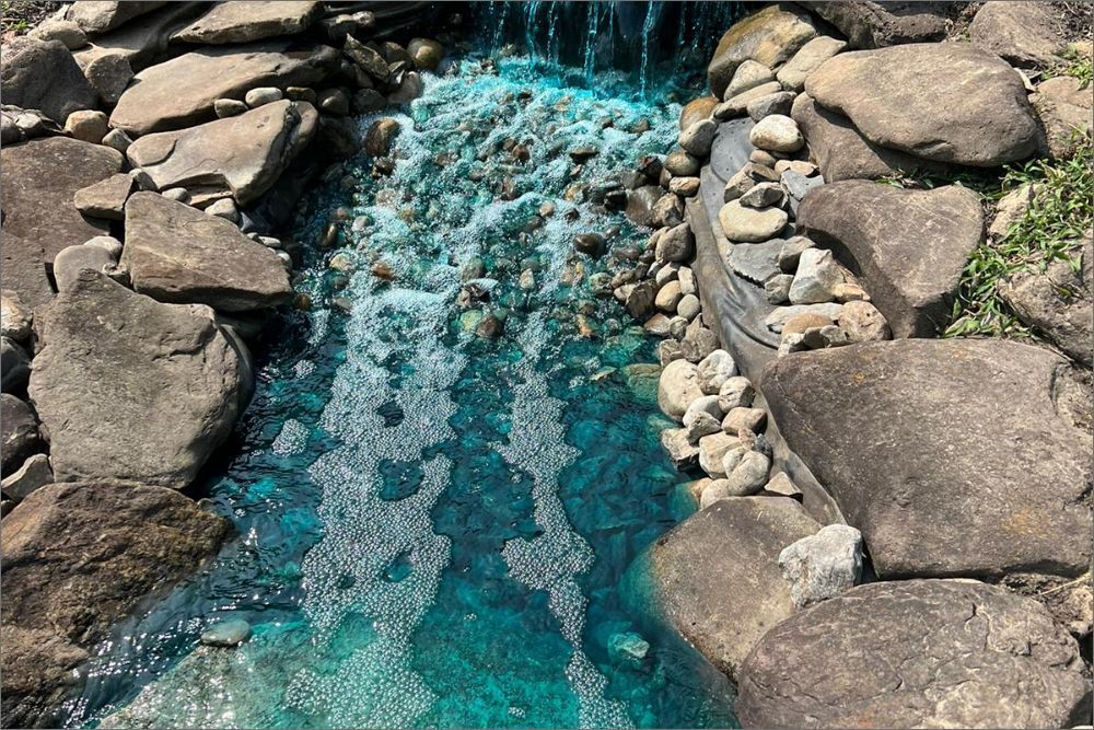 A waterfall is surrounded by rocks and a pool of water.