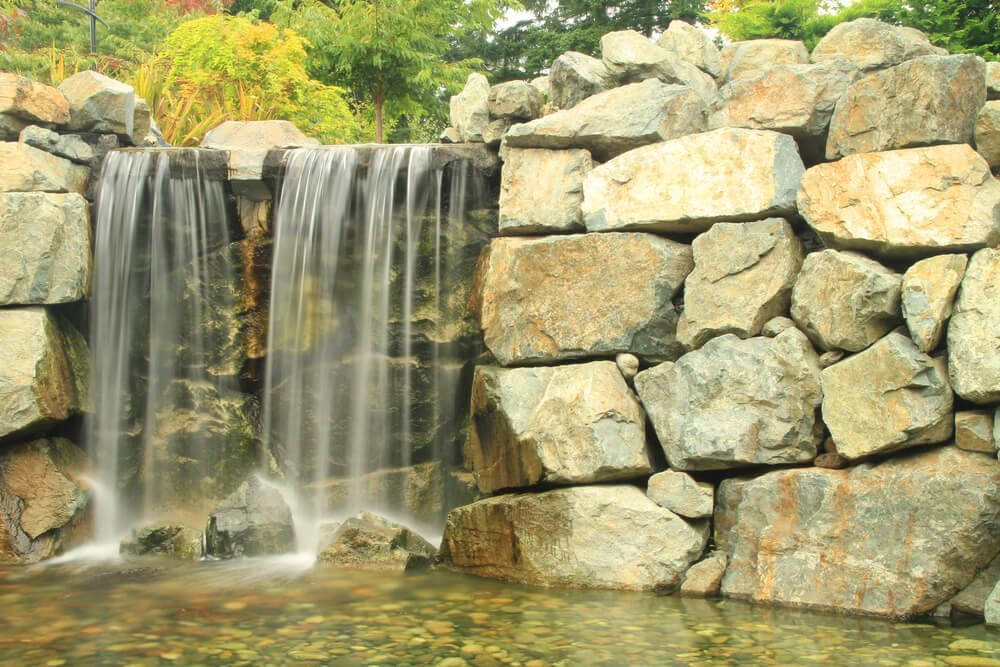 A waterfall is surrounded by rocks in a park.