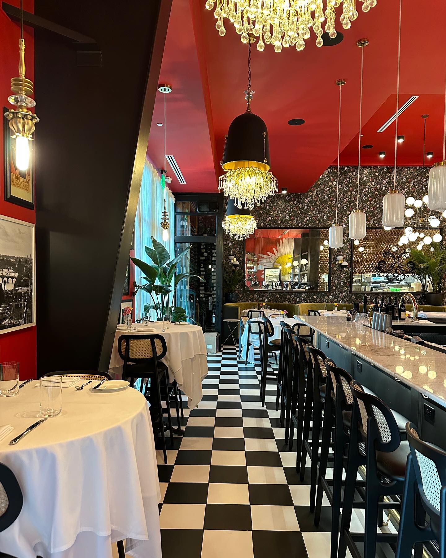 Restaurant interior: black and white checkered floor, red ceiling, black bar stools, and white tablecloths.