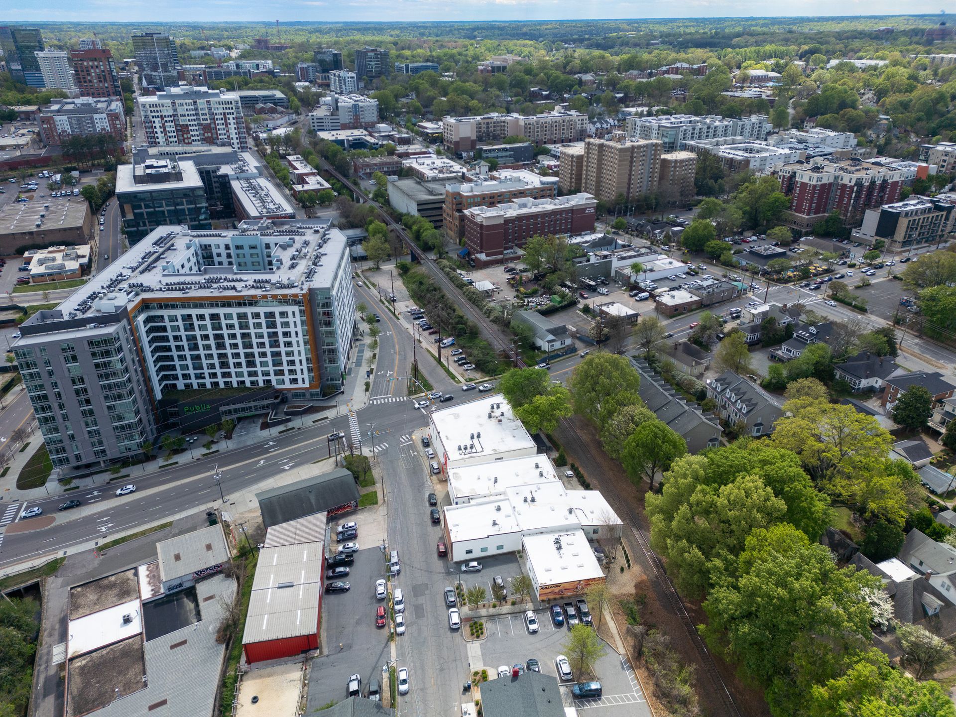 Aerial view of a city with buildings, trees, and roads. Gray and red buildings dominate the scene.