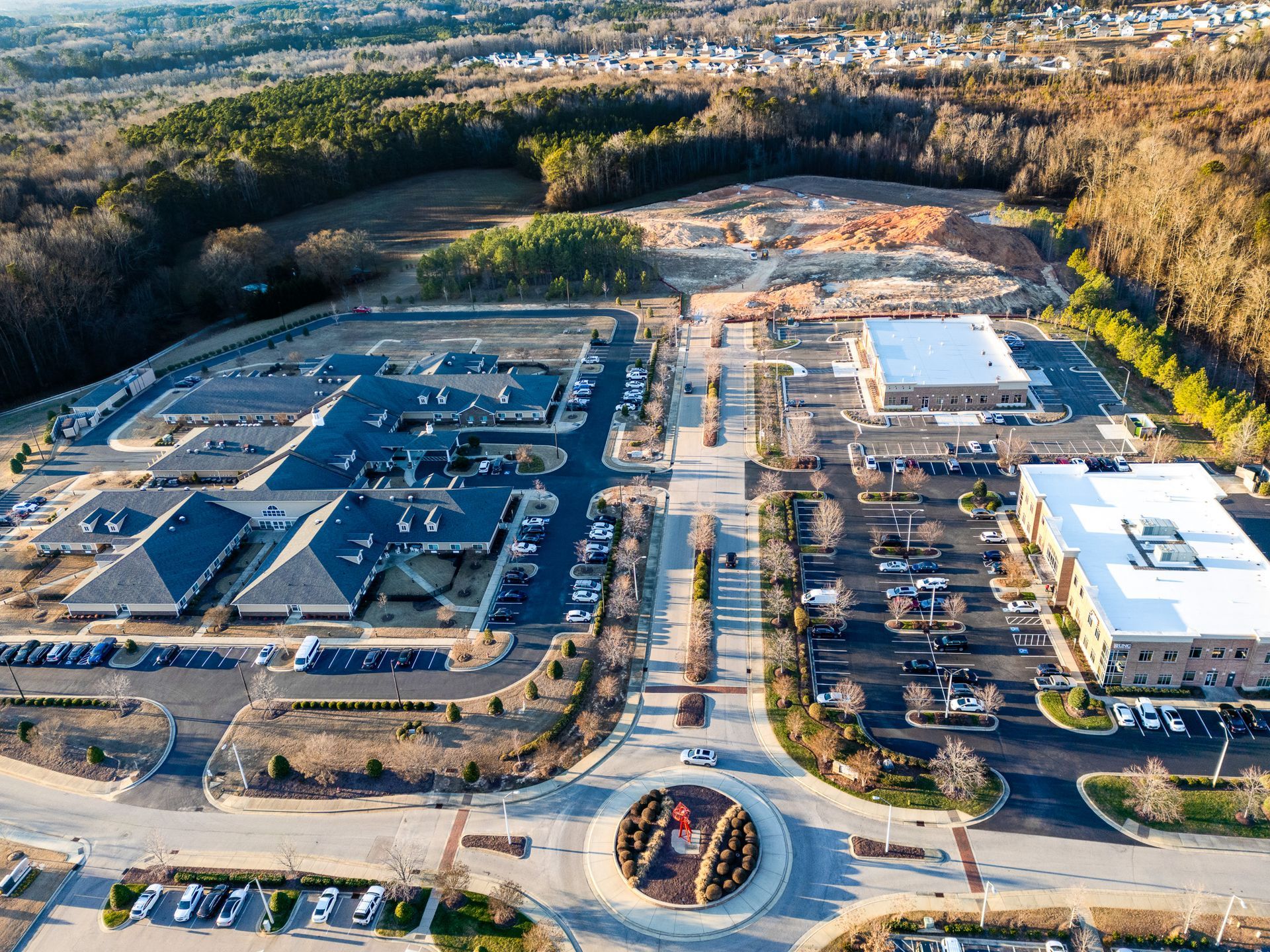 Aerial view of a commercial area with buildings, roads, parking, and a roundabout.