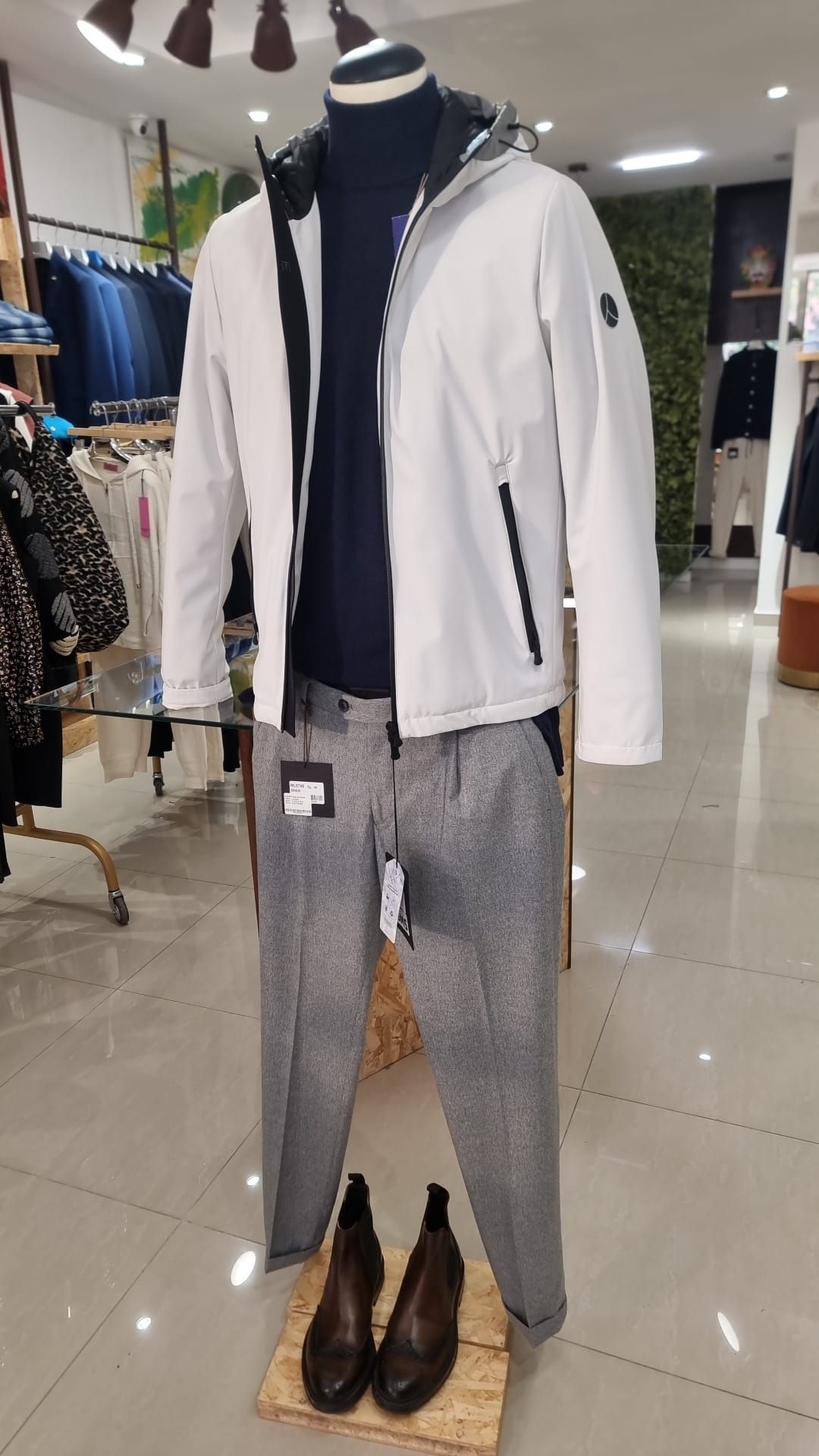 Un manichino indossa una giacca bianca e pantaloni grigi.