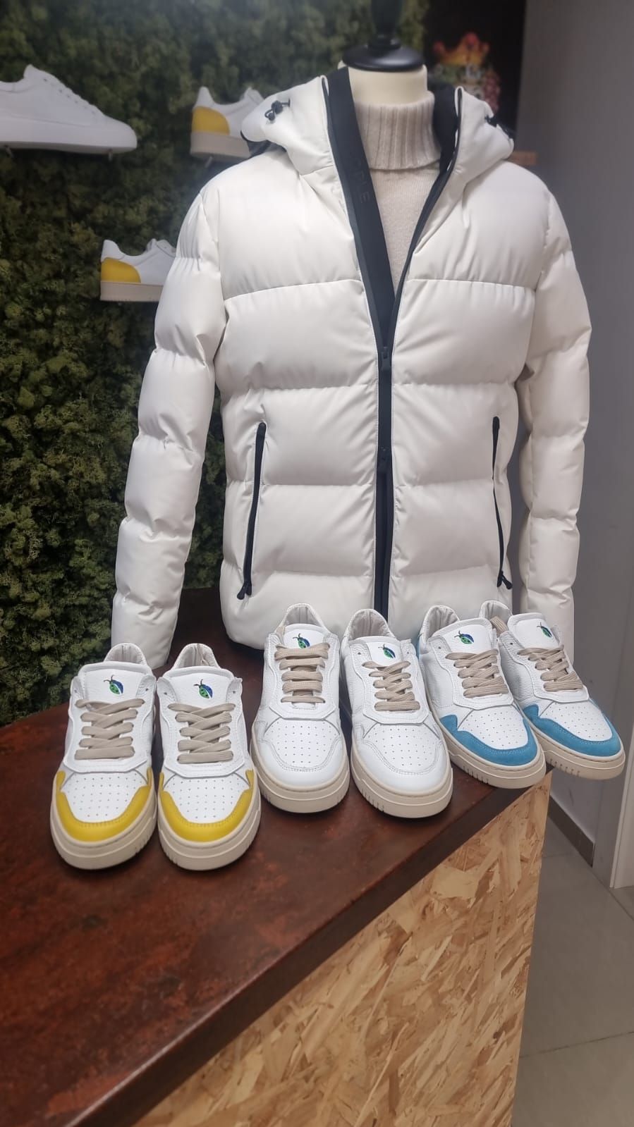 Una giacca bianca e delle scarpe da ginnastica sono appoggiate su un tavolo di legno.