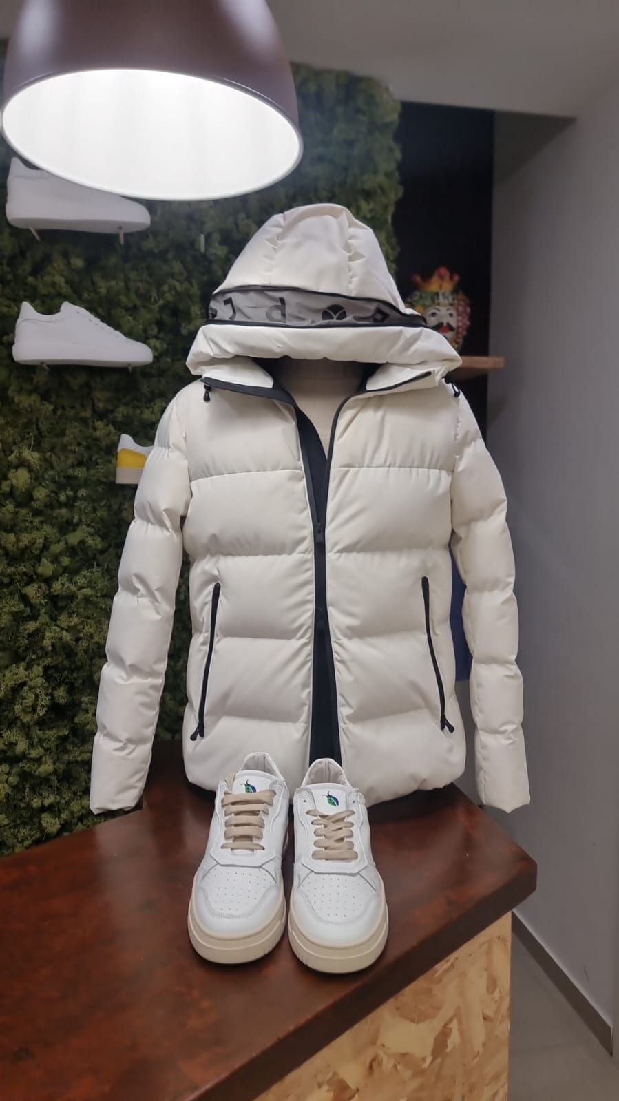 Una giacca bianca e un paio di scarpe da ginnastica bianche sono su un tavolo.
