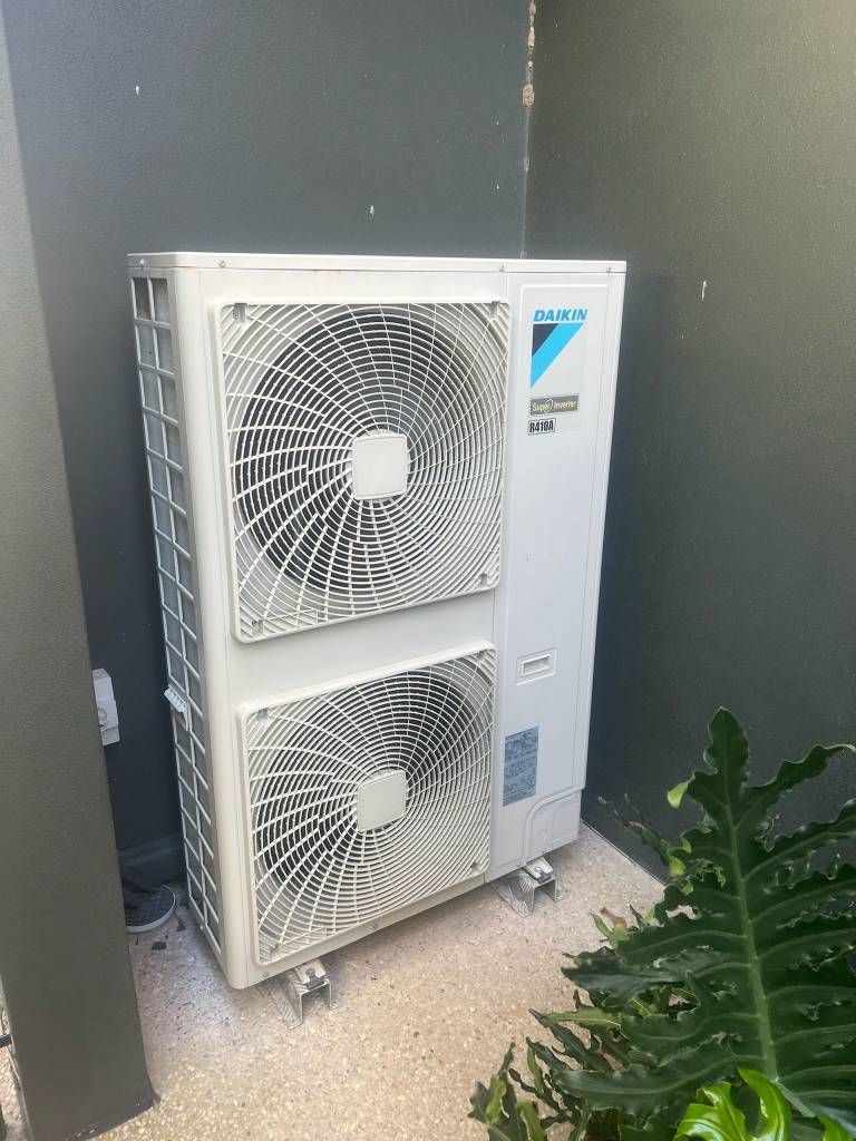 A Large Air Conditioner is Sitting Outside Next to a Wall — Kilowatts & Cool Whitsundays In Strathdickie, QLD