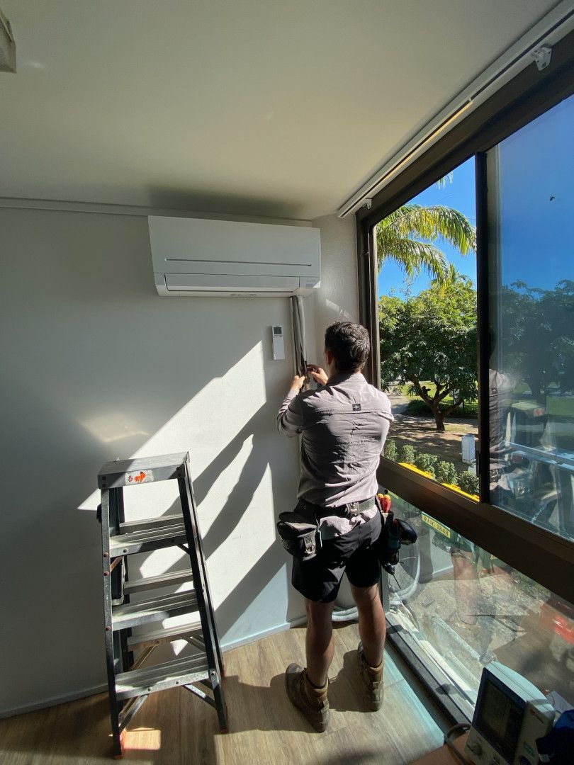 A Person Fixing Organising The Cables Of An Air Conditioning Unit — Kilowatts & Cool Whitsundays In Strathdickie, QLD