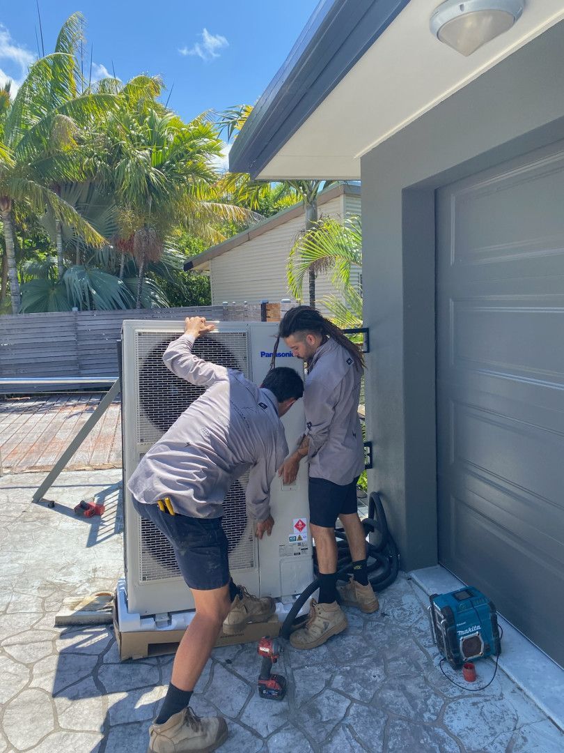 Two Men Installing Lifting An Air Conditioner Unit — Kilowatts & Cool Whitsundays In Strathdickie, QLD