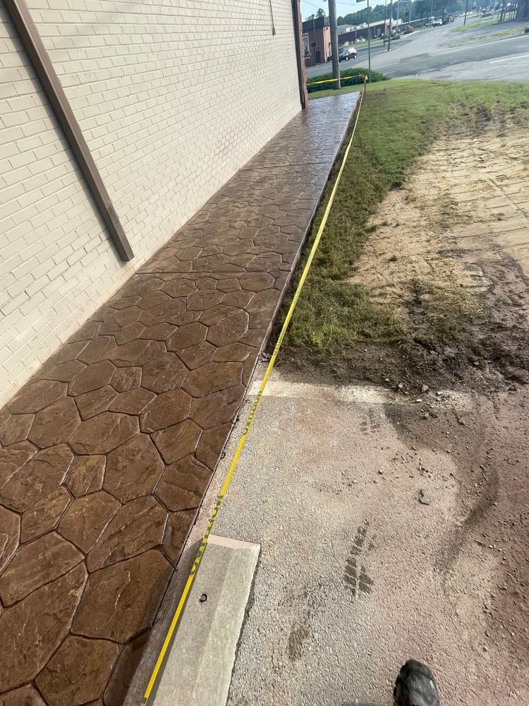 A person is measuring a sidewalk next to a building with a tape measure.