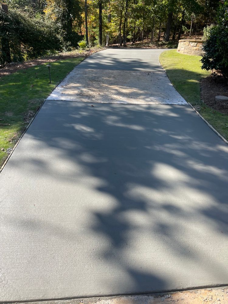 A concrete driveway going through a lush green field.