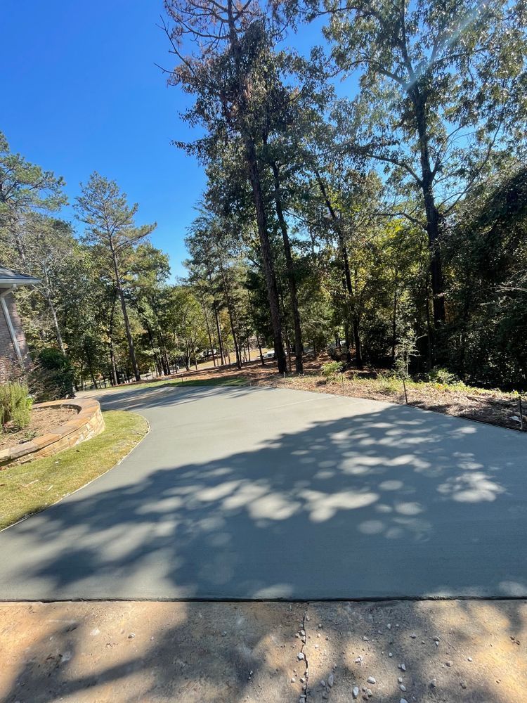 A concrete driveway surrounded by trees on a sunny day.