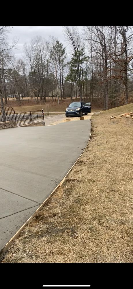 A black truck is parked on the side of a concrete driveway.