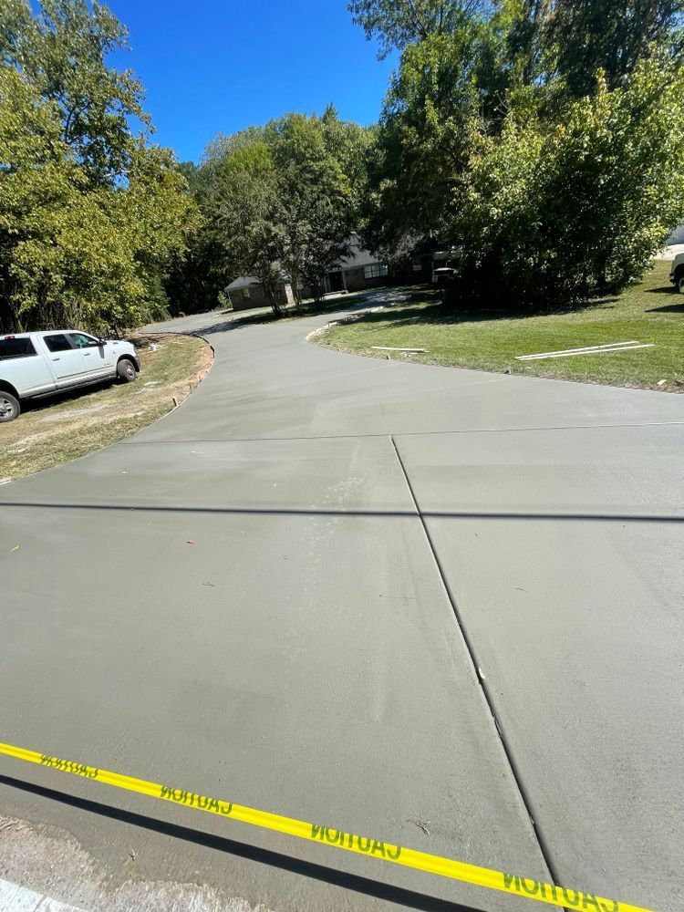 A concrete driveway with a white van parked on the side of it.