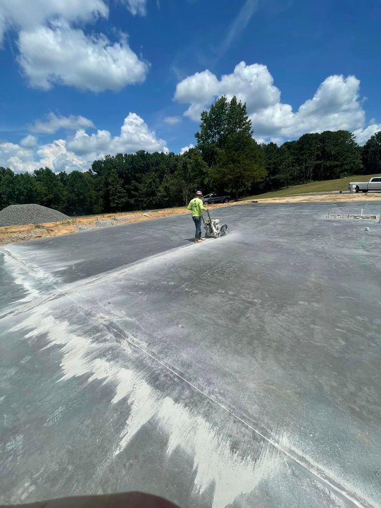 A man is walking on a concrete surface with a machine.