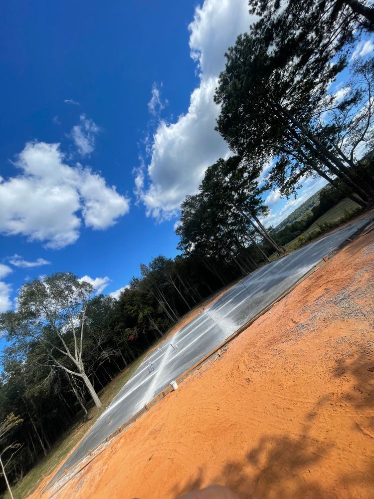 A basketball court in the middle of a field with trees in the background.