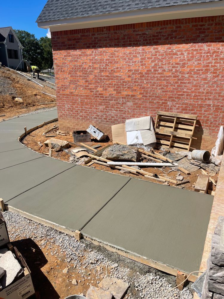 A concrete walkway is being built in front of a brick house.