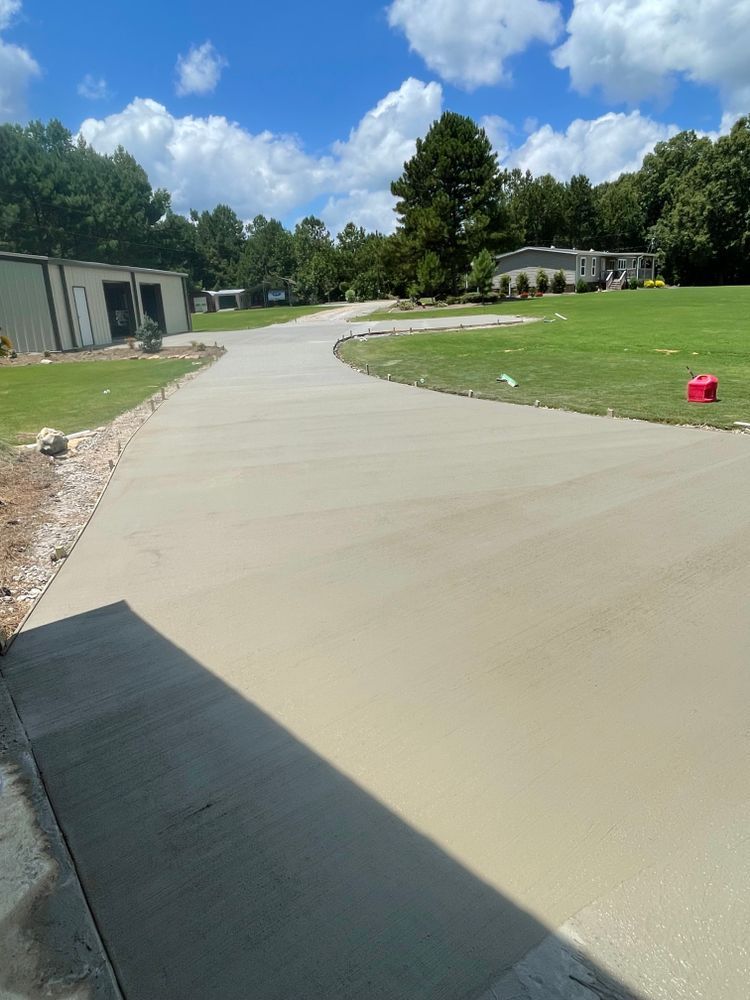 A concrete driveway going through a grassy field.
