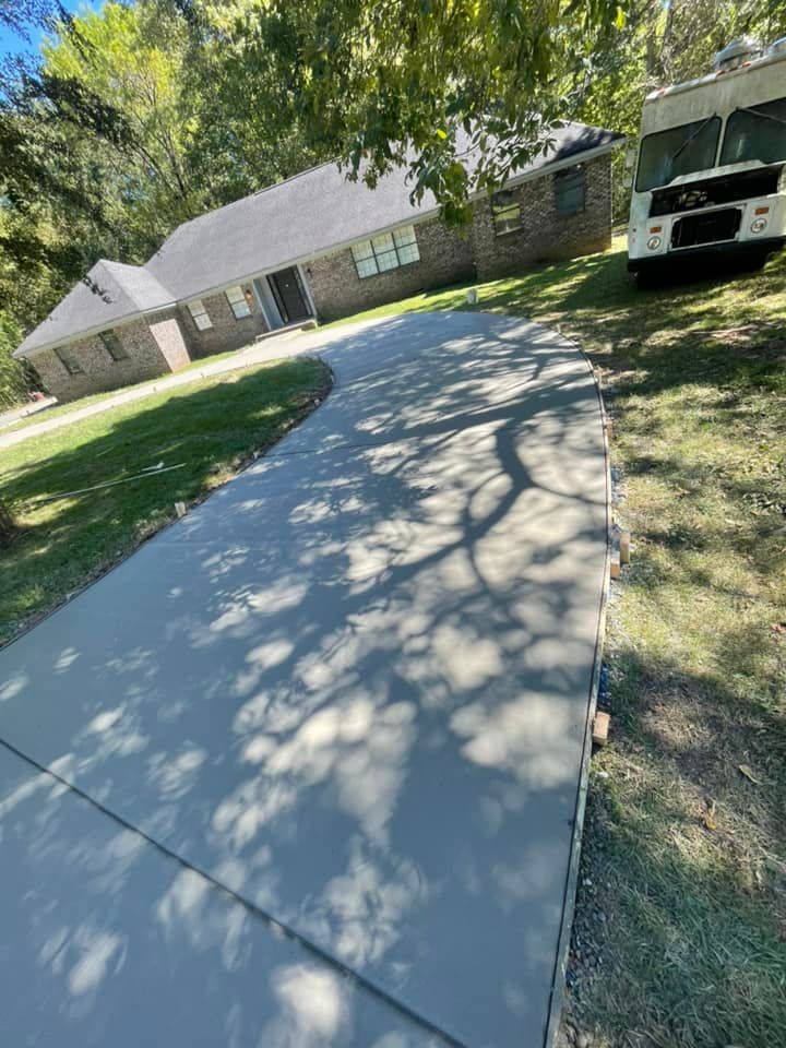 A concrete driveway leading to a house with a white van parked on the side of it.