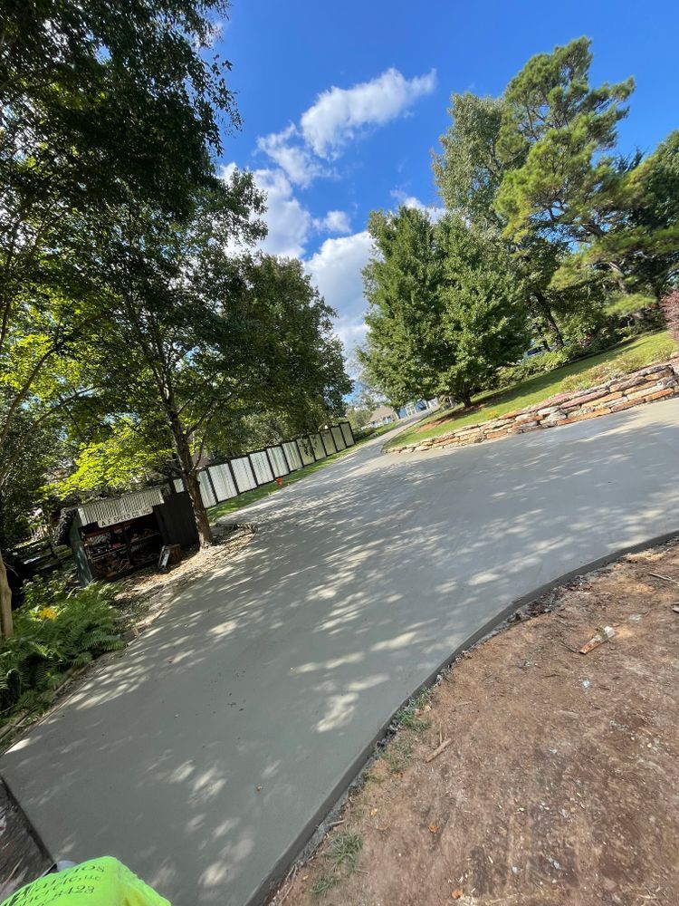 A concrete driveway with trees on both sides and a blue sky in the background.