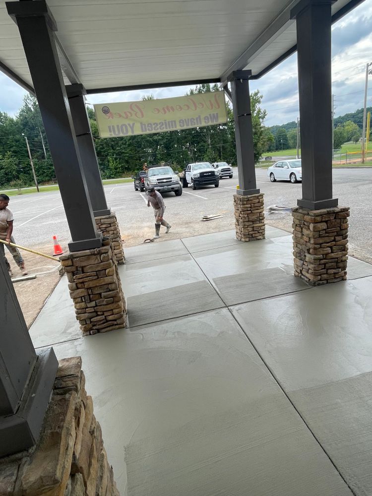 A man is standing under a covered walkway next to a parking lot.