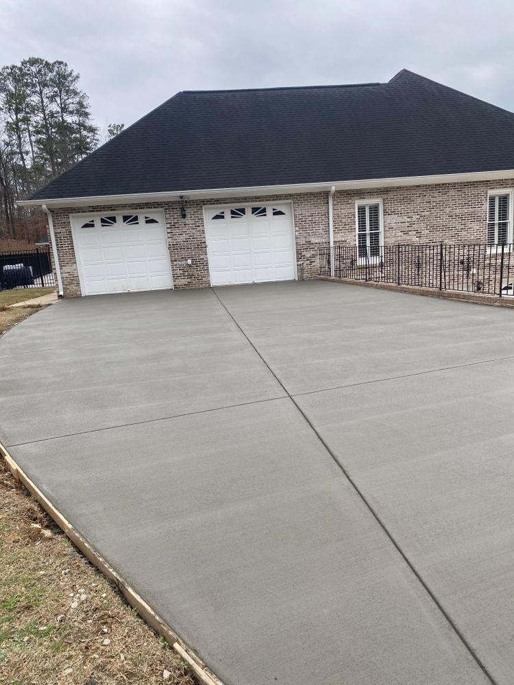 A brick house with two garage doors and a concrete driveway in front of it.