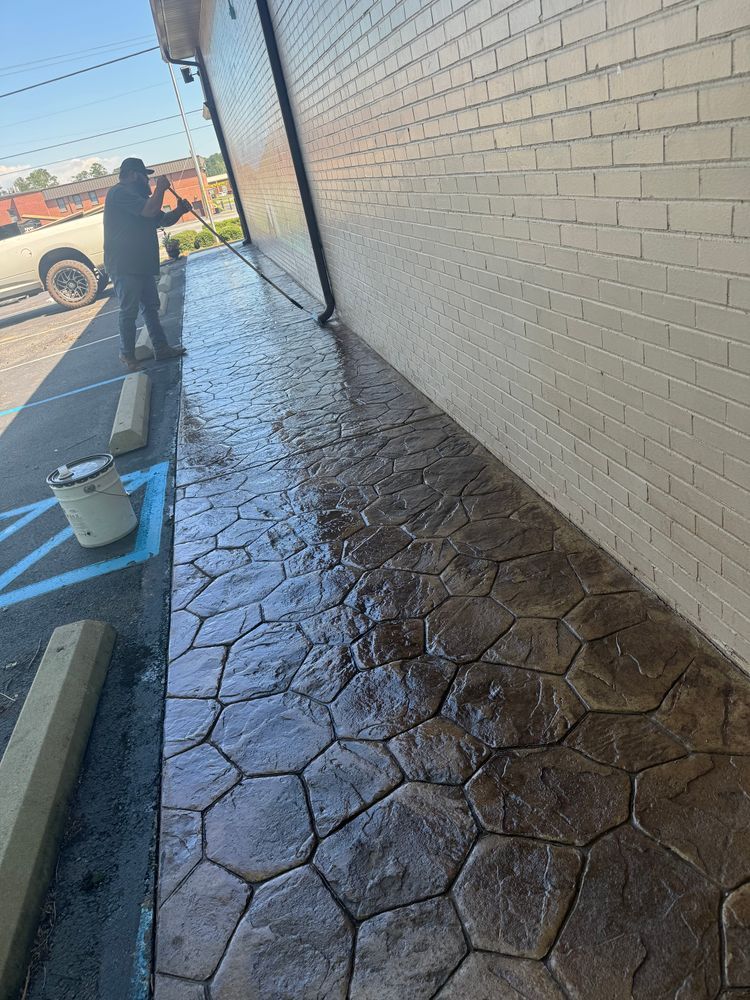 A man is standing on a sidewalk next to a brick building.