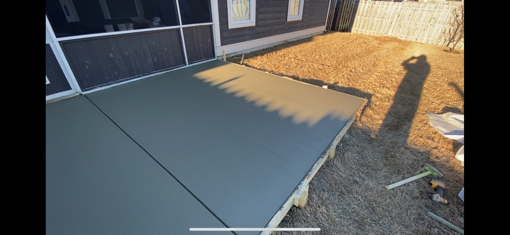 A concrete patio is being built in front of a house.
