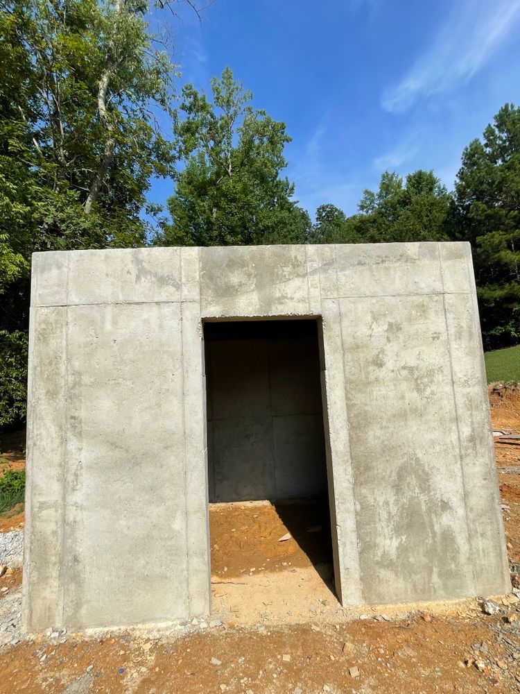 A concrete building with a door in the middle of a dirt field.