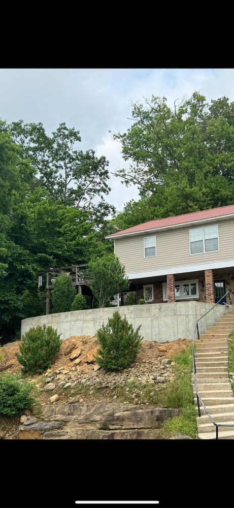 A house is sitting on top of a hill next to a river surrounded by trees.