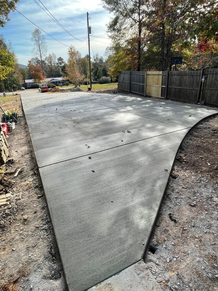 A concrete driveway is being built next to a wooden fence.