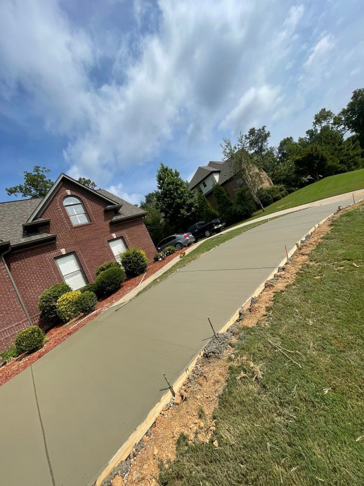A concrete driveway is being built in front of a brick house.