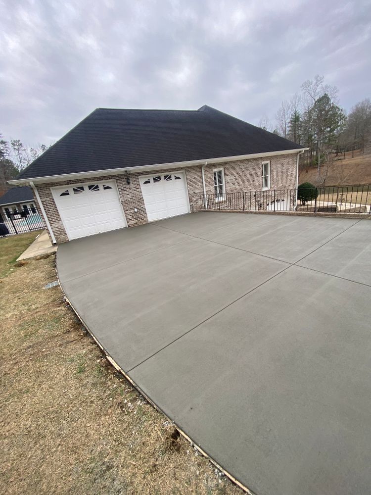 A brick house with a concrete driveway in front of it.