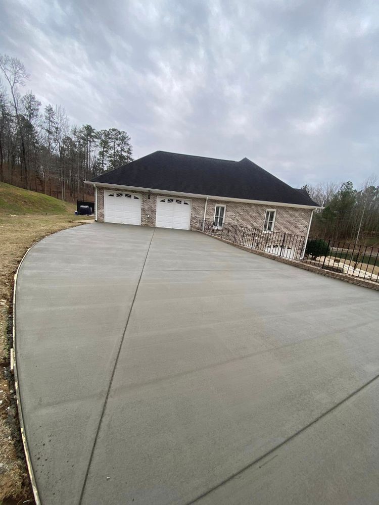 A concrete driveway leading to a house with two garage doors.