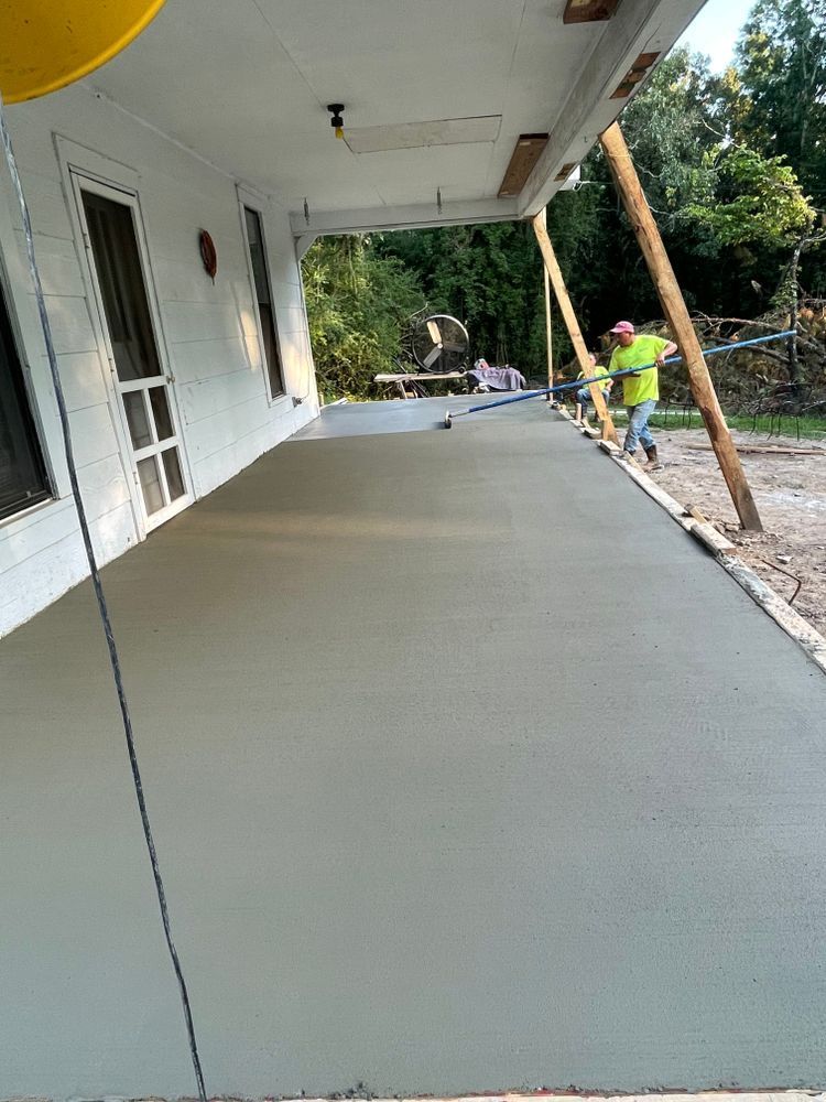 A man is pouring concrete on a porch.