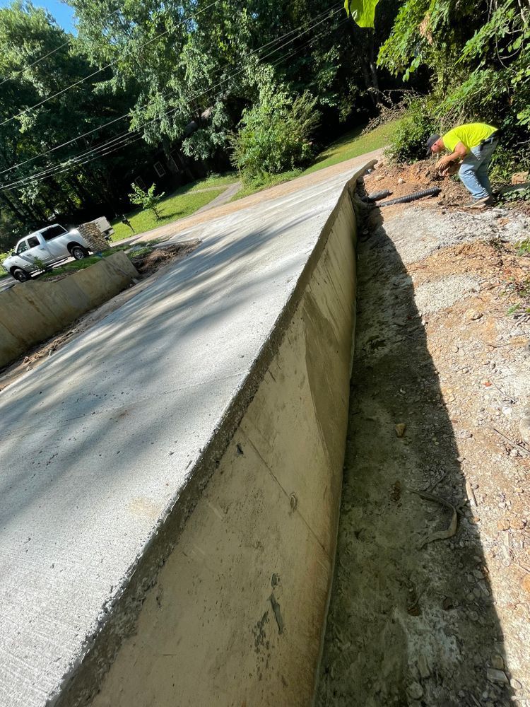 A man is working on a concrete wall on the side of a road.