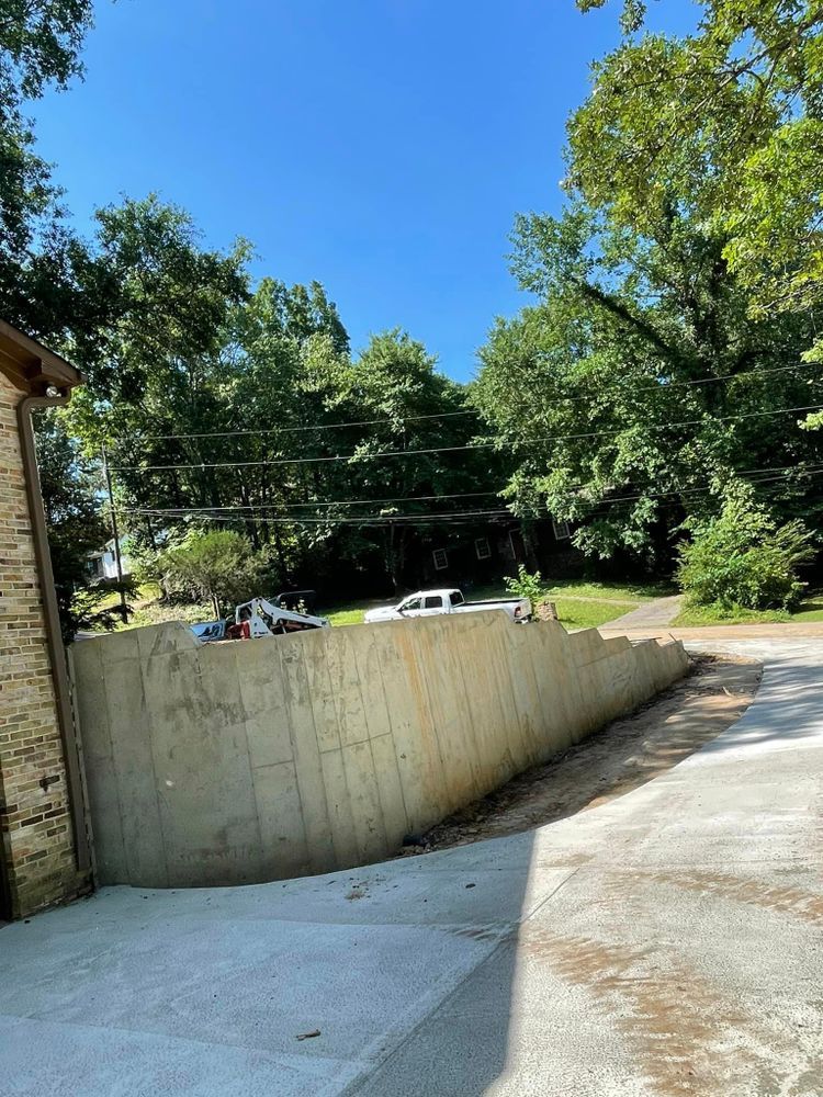 A concrete wall along the side of a road with trees in the background.