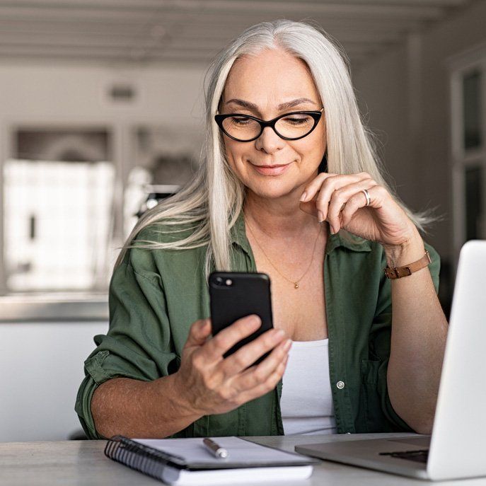 Stylish senior woman messaging with phone stock photo