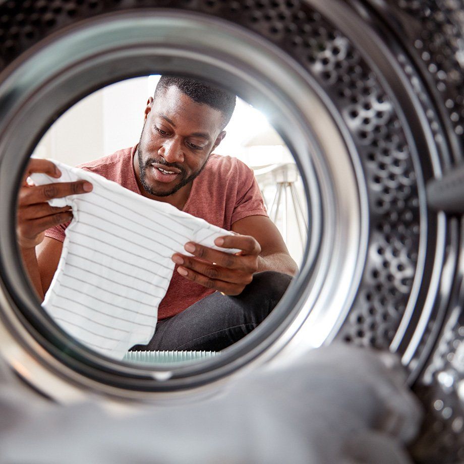 man looking at a onesie through a washing machine