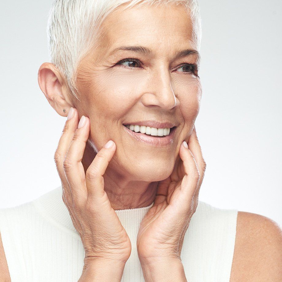 mature woman with white short hair touching her face