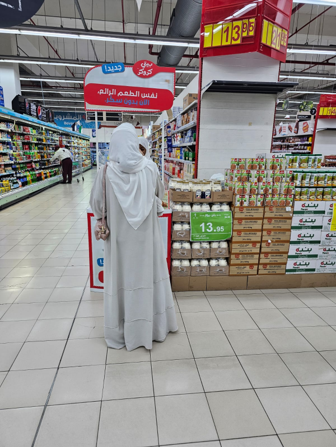 A woman in a white dress is standing in a grocery store