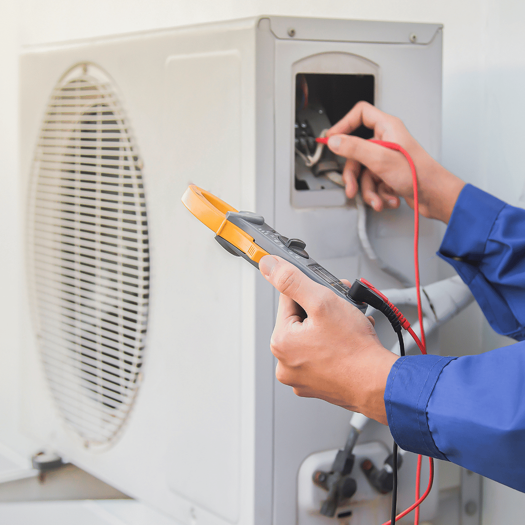 A person is working on an air conditioner with a pair of pliers.