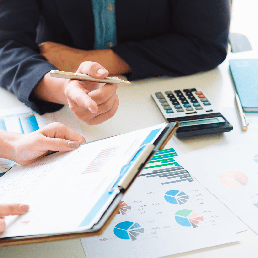 Two people are sitting at a table with a calculator and a clipboard.