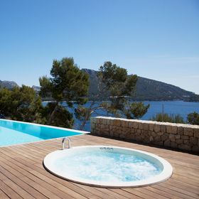 Una vasca idromassaggio si trova su un ponte di legno accanto a una piscina