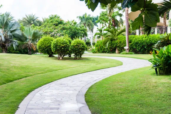 A brick walkway in a park surrounded by grass and trees.