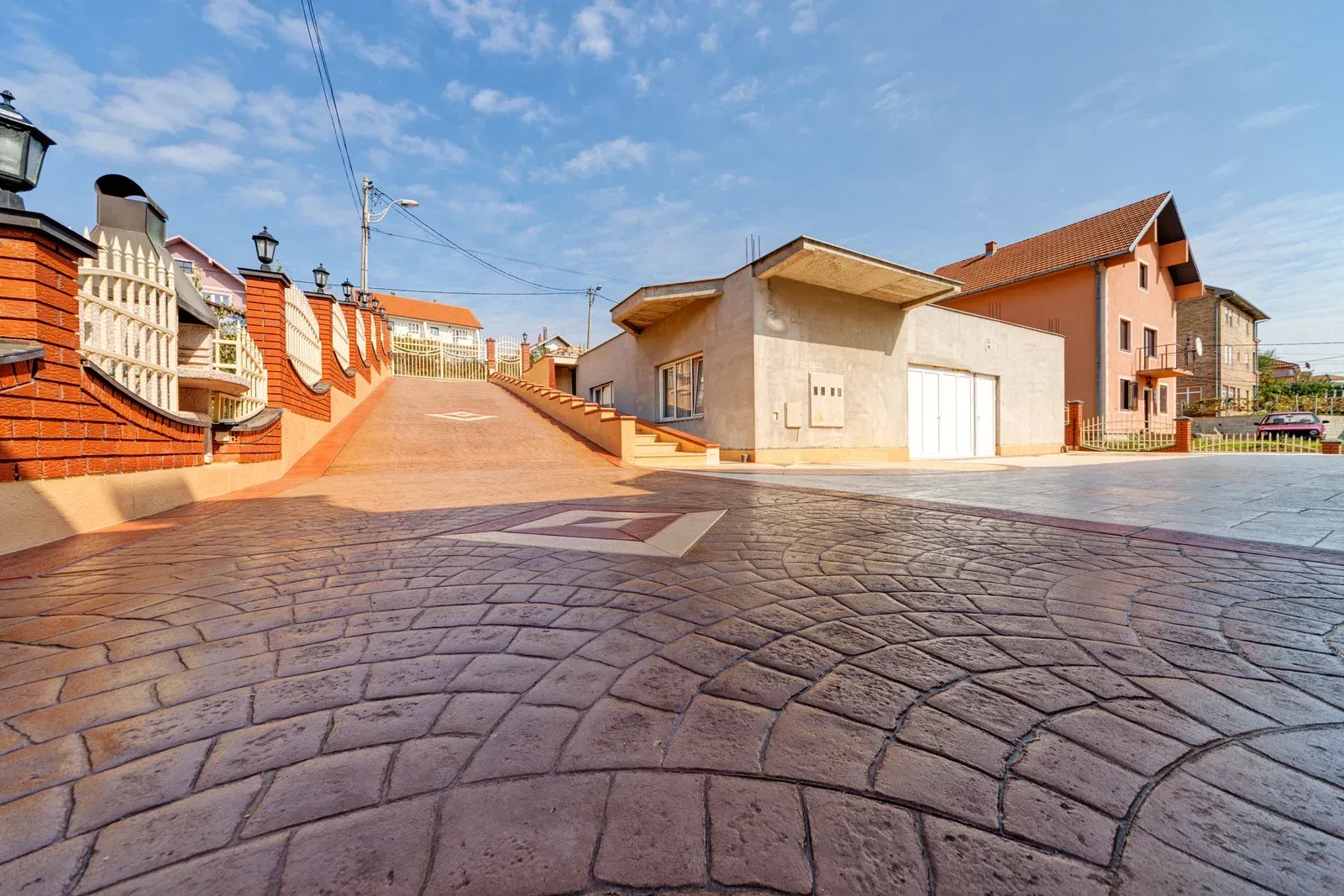 A brick walkway leading to a house in a residential area.