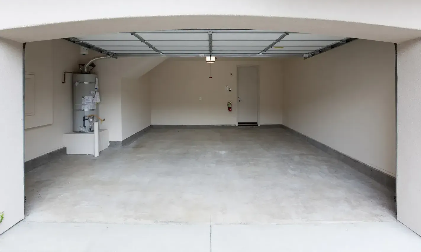 An empty garage with a water heater and a door.