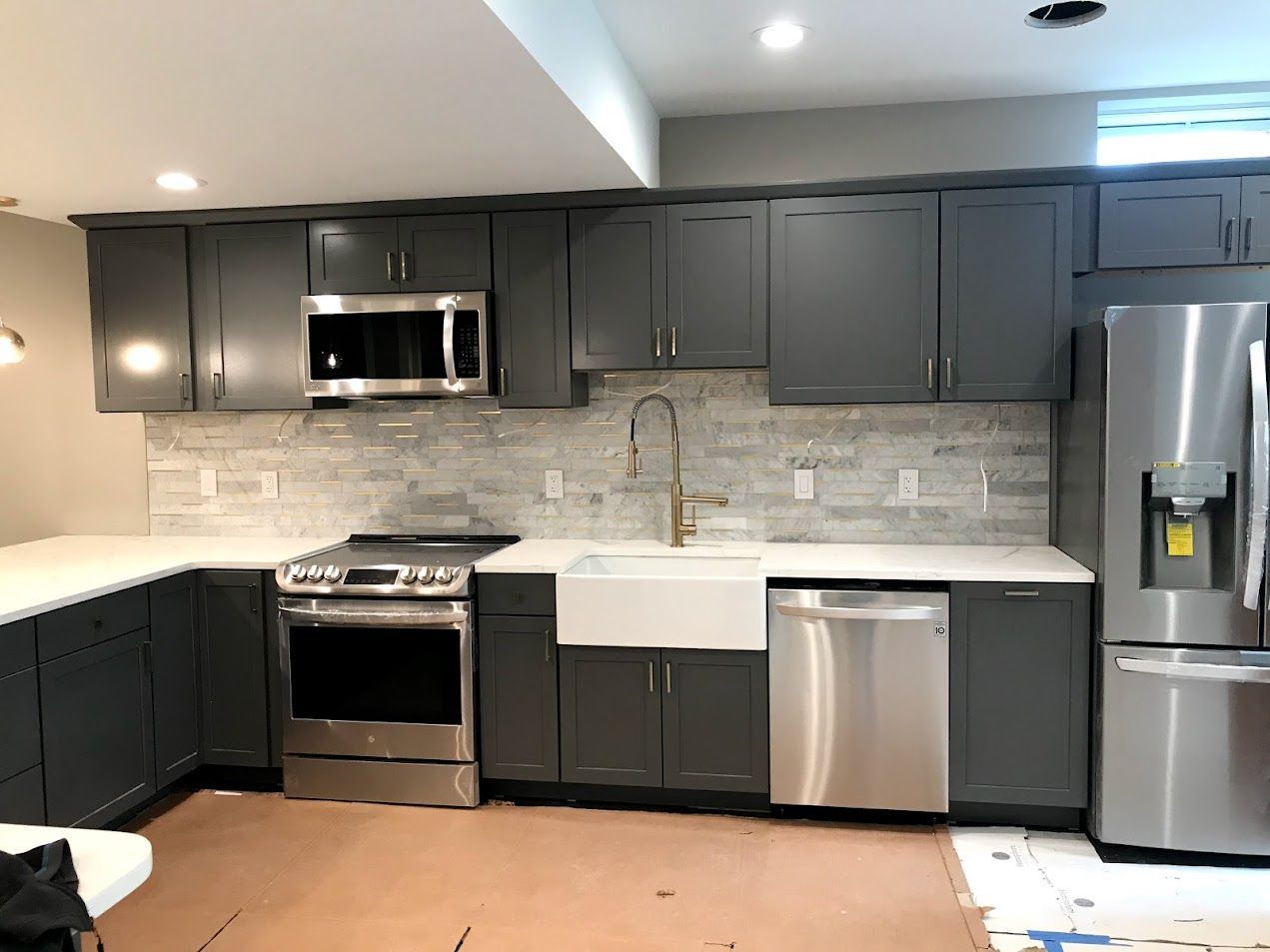 A kitchen with gray cabinets and stainless steel appliances