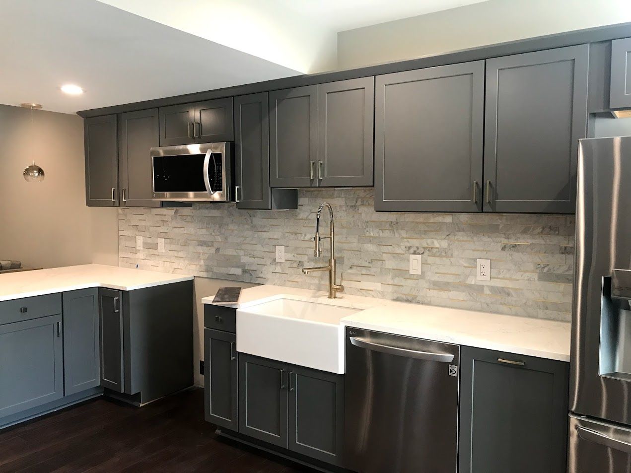 A kitchen with gray cabinets , stainless steel appliances , a sink , and a refrigerator.